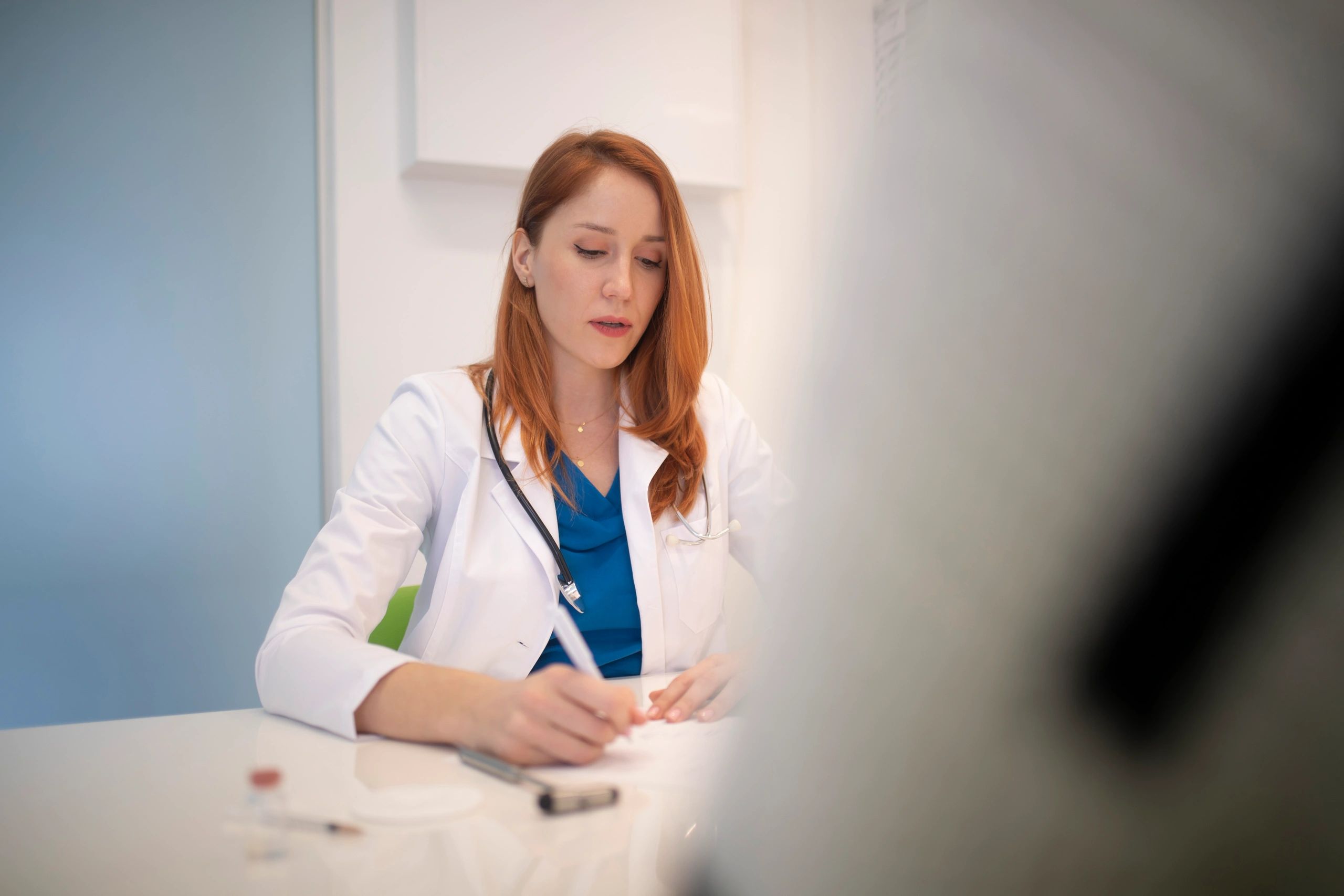 Doctor writing notes during a patient consultation